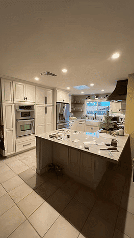 Modern kitchen with white cabinetry, marble countertop, and stainless steel appliances.
