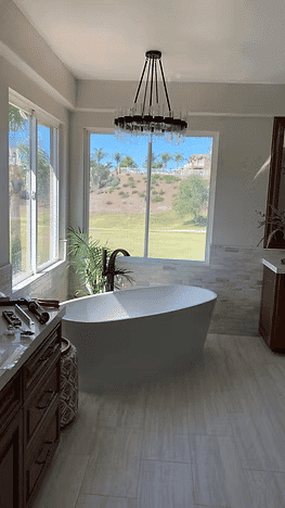 Modern bathroom with a freestanding tub, large windows, and scenic outdoor view.