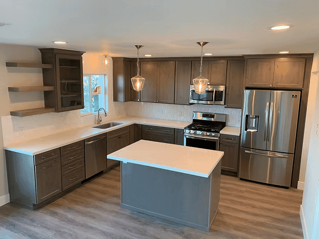 Modern kitchen with gray cabinets, stainless steel appliances, and a central island.
