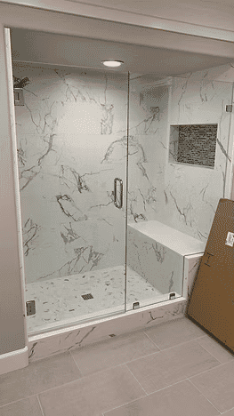 Modern glass shower enclosure with marble walls and stone tile floor. Elegant bathroom design.