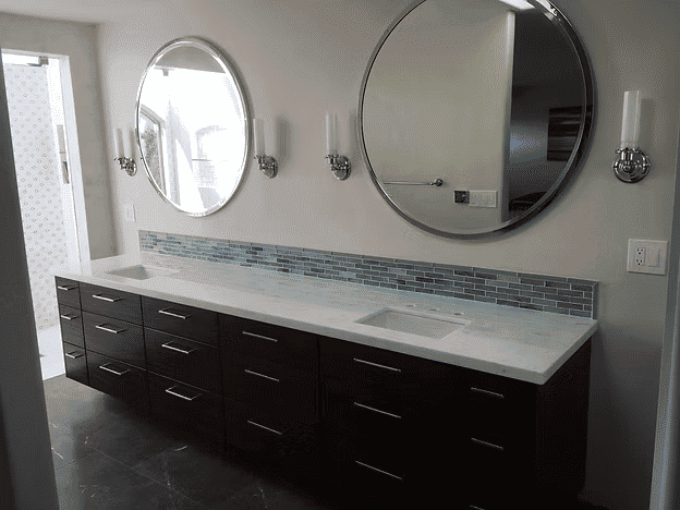 Modern bathroom with double mirrors, marble countertop, and sleek dark cabinetry.