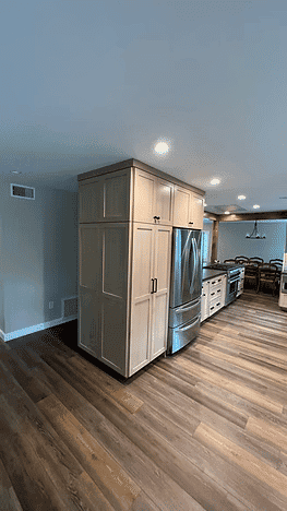 Modern kitchen with light wood cabinets, stainless steel appliances, and hardwood floors.