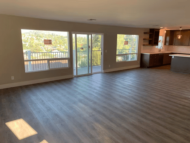 Spacious living room with sliding glass doors and kitchen view, featuring modern finishes.