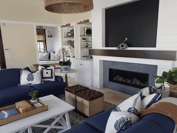 Modern living room with blue sofas, a fireplace, and stylish decor featuring plants and accessories.
