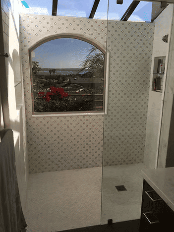 Spacious shower with large window overlooking scenic view and decorative tile walls.