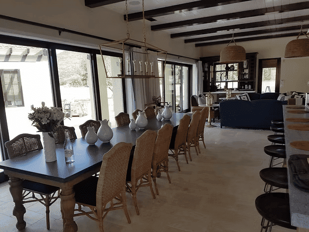 Modern dining room with a large wooden table, wicker chairs, and stylish decor.