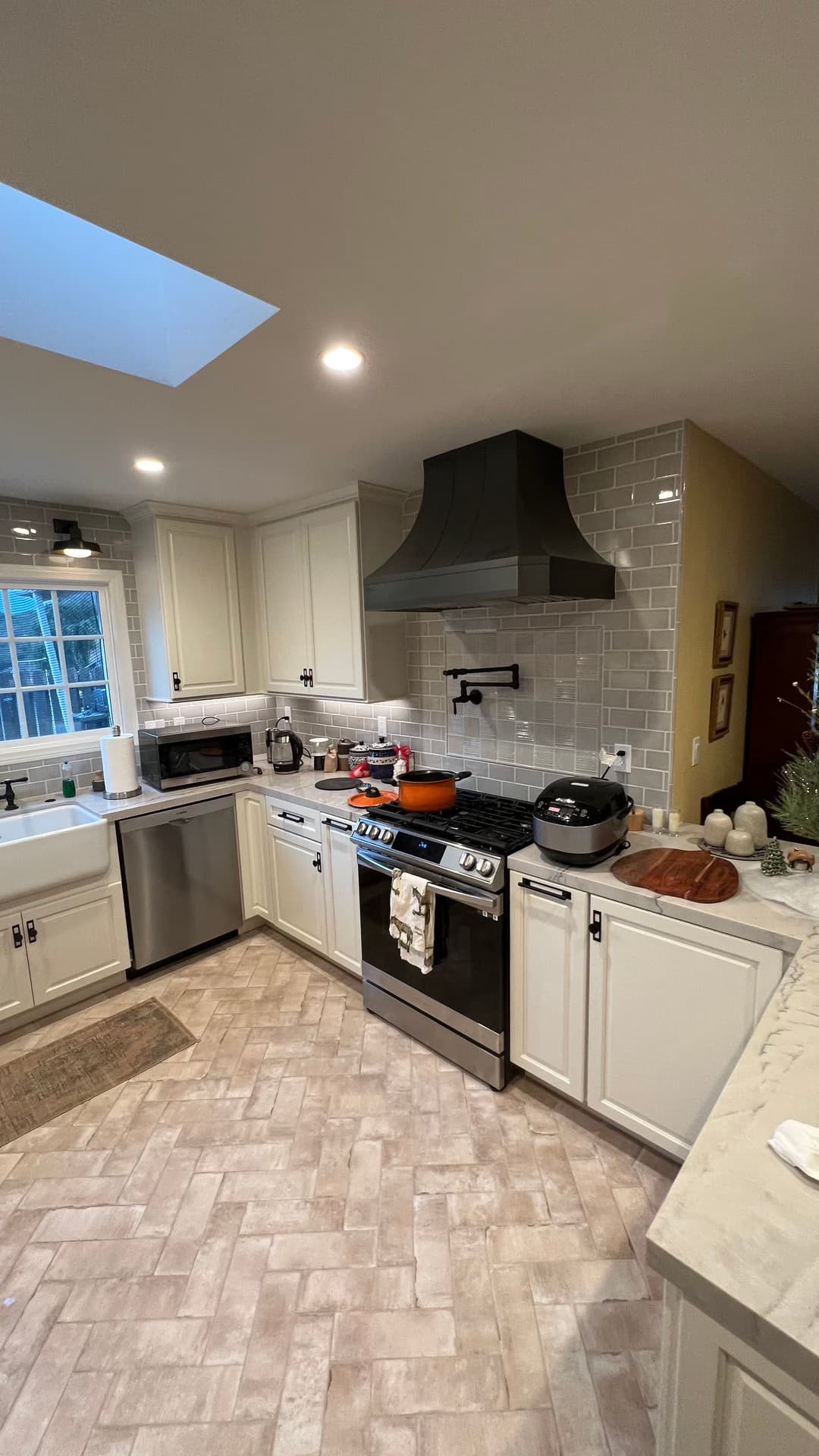 Modern kitchen with white cabinetry, stainless steel appliances, and a skylight above.