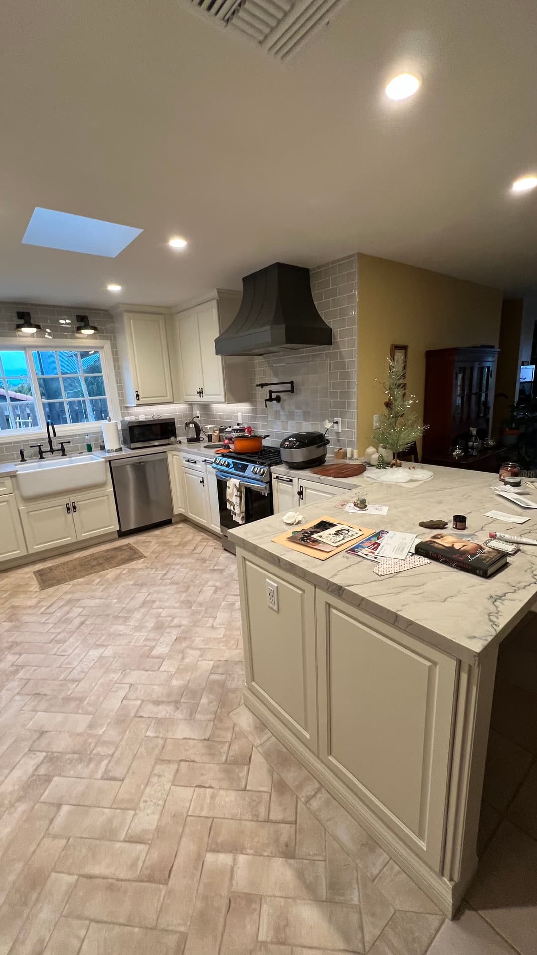 Modern kitchen with marble countertops, stainless steel appliances, and herringbone tile floor.