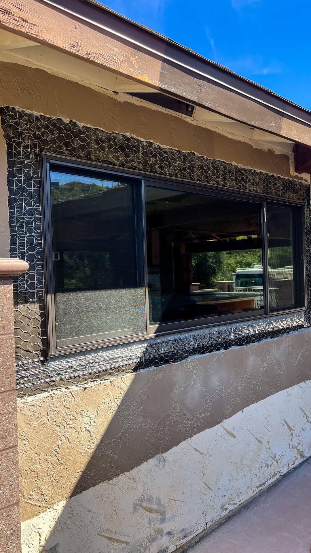 Modern black window with wire mesh detail on exterior wall of a house.