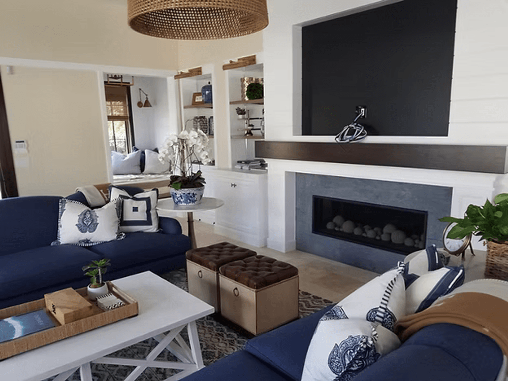 Modern living room with navy blue sofas, decorative pillows, and a stylish fireplace.