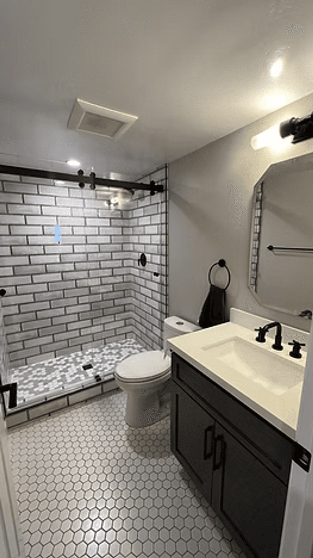 Modern bathroom design featuring a tiled shower, black fixtures, and a stylish sink vanity.