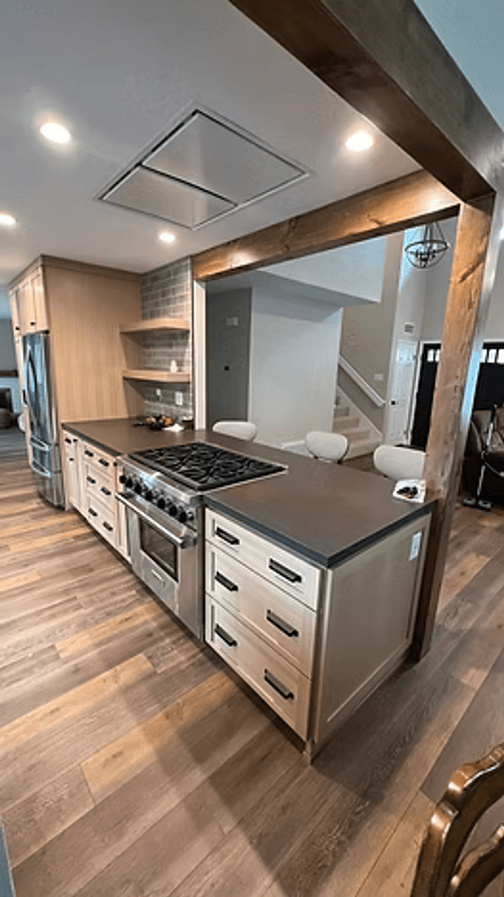 Modern kitchen with wooden accents, large island, and stainless steel appliances.